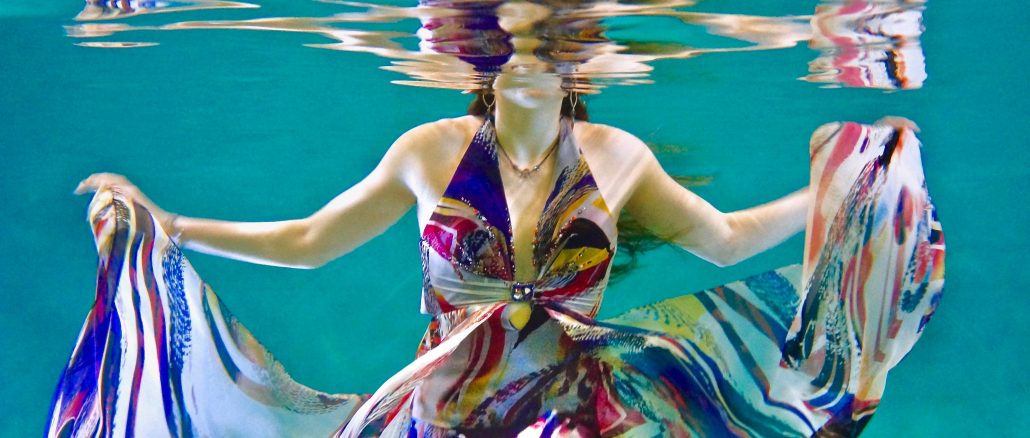 Bruce Christianson, "Underwater Fashion shoot testing with Sophie in a brightly colored flowing dress swirling with reflections on the under-surface of the pool," photograph, Unsplash.